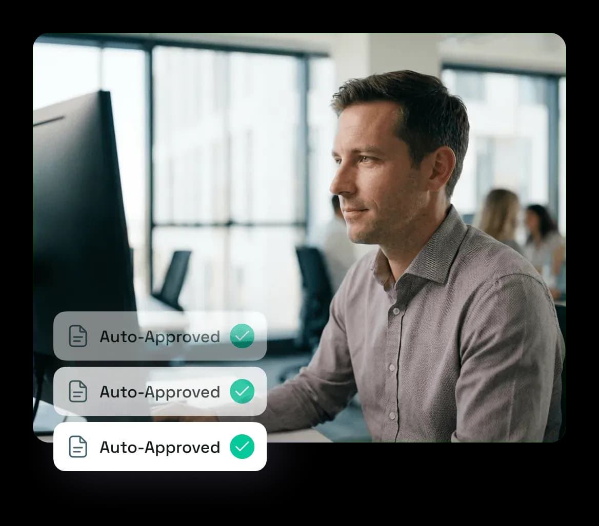Man working on a computer in a modern office with three layered 'Auto-Approved' icons displayed beside him.