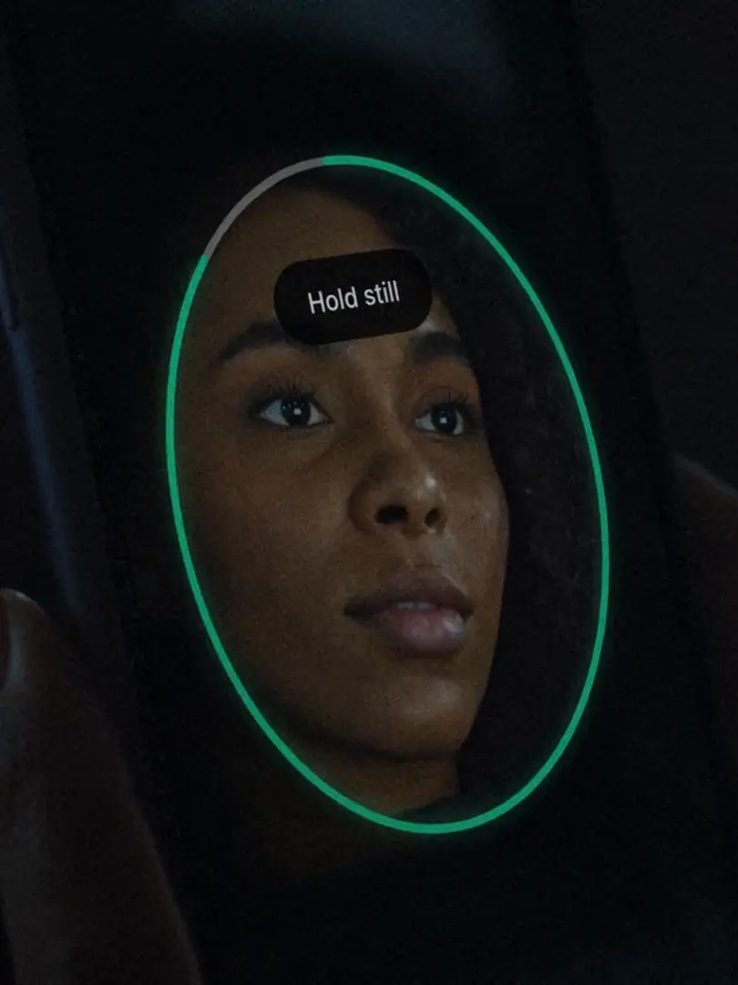 The Agemin camera step on a phone: her face inside the oval guide, Hold still.